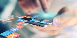 Hands using a smartphone with colorful application icons floating above the screen.