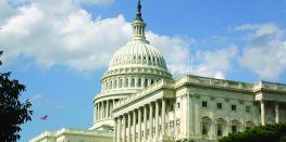 Close-up of the dome of the United States Capitol Building against a partly cloudy sky.