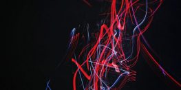 Abstract light painting with red and blue streaks against a dark background.